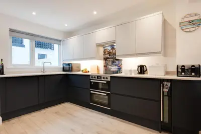 a kitchen with black cabinets and white appliances at 3 Bed in Looe oc-l30071 in Looe