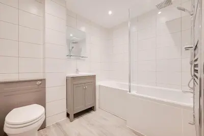 a white bathroom with a toilet and a bath tub at 3 Bed in Looe oc-l30071 in Looe