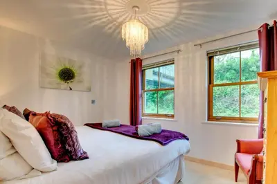 a bedroom with a large white bed and windows at 2 Bed in Looe oc-l30065 in Looe