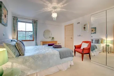 a bedroom with a large bed and a red chair at 2 Bed in Looe oc-l30065 in Looe