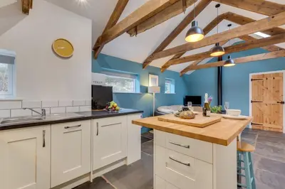 a kitchen with white cabinets and blue walls at 1 Bed in Duloe oc-l30057 in Duloe