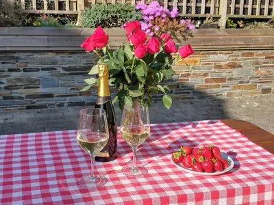 a table with two glasses of wine and a vase of roses at The Mill in Tintagel