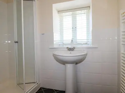 a white bathroom with a sink and a window at The Mill in Tintagel