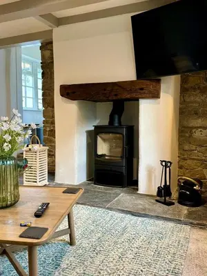 a living room with a stone fireplace with a tv at 2 Penmayne Cottage in Saint Minver