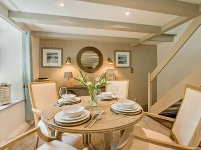 a dining room with a table and a mirror at 2 Penmayne Cottage in Saint Minver