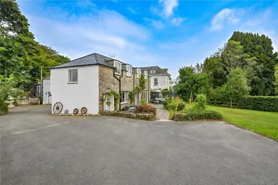 a large white house with a driveway at Wykeham Coach House in Looe