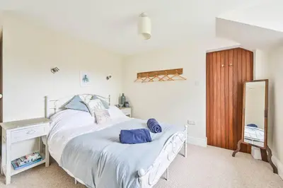 a bedroom with a large white bed with blue pillows at Wykeham Coach House in Looe