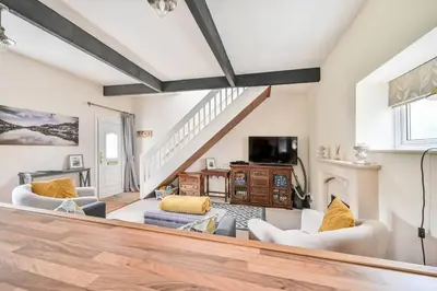 a living room with two chairs and a fireplace at Wykeham Coach House in Looe