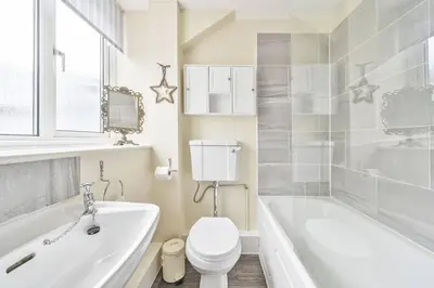 a bathroom with a white tub and a toilet and a sink at Wykeham Coach House in Looe