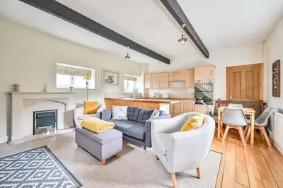 a living room with a couch and chairs and a kitchen at Wykeham Coach House in Looe