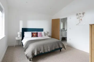 a white bedroom with a large bed and a sink at The Hideaway, Modern 3 bed in Tintagel, Cornwall in Tintagel