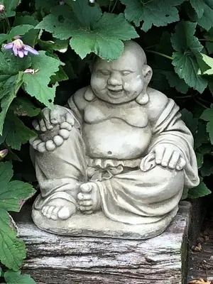 a statue of a baby sitting on a stump at Vine Cottage in Penpillick