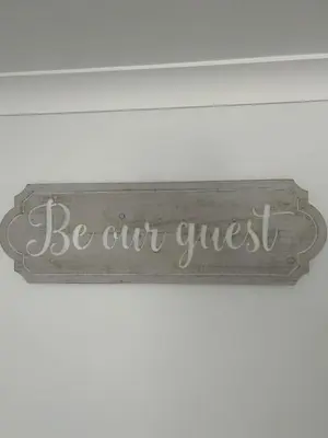 a sign that says be our guest on a wall at Ruby's Den in Carbis Bay