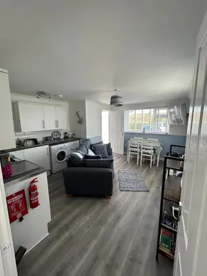 a living room with a couch and a kitchen at Ruby's Den in Carbis Bay