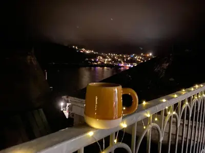 a coffee cup sitting on a balcony at night at The Captain’s 4 Bed Penthouse in Fowey