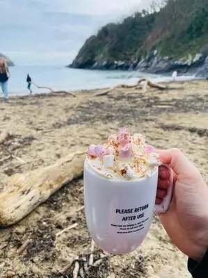 a person holding a cup of ice cream on a beach at The Captain’s 4 Bed Penthouse in Fowey