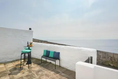 a white wall with two chairs and the ocean at 2 Bed in Porthleven oc-marin2 in Porthleven