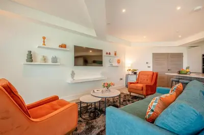 a living room with a blue couch and two orange chairs at 3 Bed in Newquay oc-mordh in Newquay