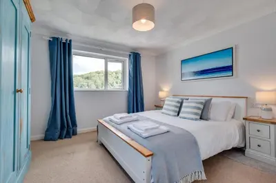 a bedroom with a bed with blue curtains and a window at 2 Bed in Looe oc-msweet in Looe