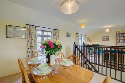 a dining room with a wooden table with flowers on it at 2 Bed in Padstow oc-p00002 in Padstow