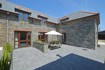 a stone house with a patio with an umbrella at 1 Bed in St. Merryn oc-nel42 in St Merryn