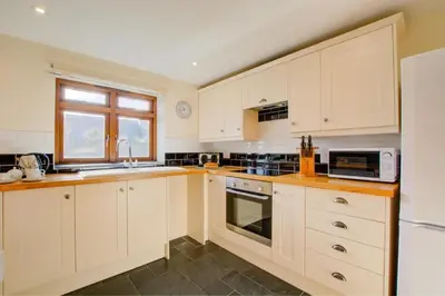 a large kitchen with white cabinets and a window at 1 Bed in St. Merryn oc-nel42 in St Merryn