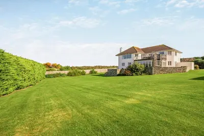 a large grassy yard with a large house at 6 Bed in Padstow oc-p00006 in St Merryn