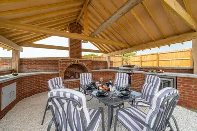 a patio with a table and chairs and a brick oven at 4 Bed in Horningtops oc-northt in Menheniot
