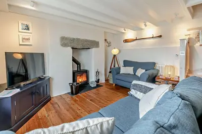 a living room with a blue couch and a fireplace at 2 Bed in Porthleven oc-nights in Porthleven