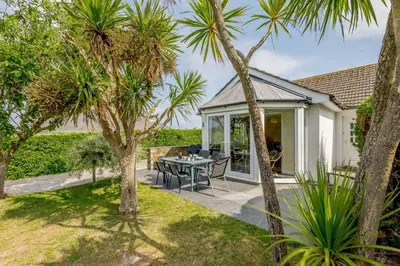 a patio with palm trees and a table and chairs at 5 Bed in Padstow oc-p00053 in St Merryn