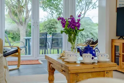 a table with a vase with purple flowers on it at 5 Bed in Padstow oc-p00053 in St Merryn