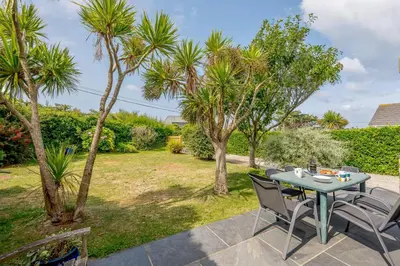 a patio with a table and chairs and palm trees at 5 Bed in Padstow oc-p00053 in St Merryn