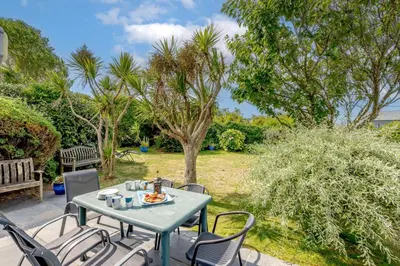 a table and chairs on a patio with trees at 5 Bed in Padstow oc-p00053 in St Merryn