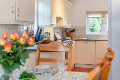 a kitchen with a table with a vase of flowers at 3 Bed in Padstow oc-p00043 in St Merryn