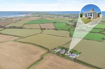 a house in a field with the ocean in the background at 3 Bed in Padstow oc-p00043 in St Merryn