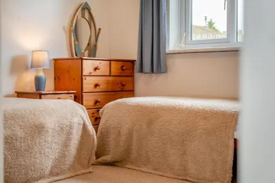 a bedroom with two beds and a dresser and a window at 3 Bed in Padstow oc-p00131 in St Merryn