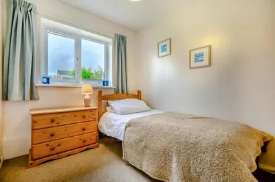 a bedroom with a bed and a dresser and a window at 3 Bed in Padstow oc-p00131 in St Merryn