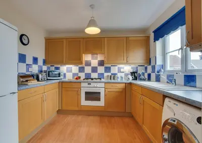 a kitchen with wooden cabinets and blue and white tiles at 3 Bed in Wadebridge oc-p00093 in Wadebridge
