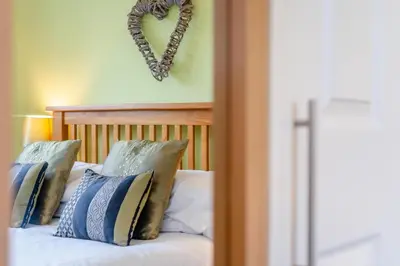 a heart shaped wreath hangs above a bed with pillows at 3 Bed in St. Merryn oc-p00114 in St Merryn