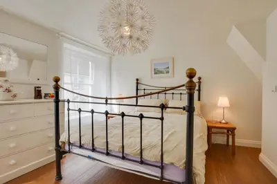 a bedroom with a black bed and a chandelier at 2 Bed in Padstow oc-p00082 in Padstow