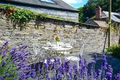 a table and chairs in a garden with purple flowers at 2 Bed in Padstow oc-p00082 in Padstow