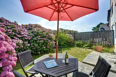 a table with a red umbrella and a bottle of wine at 4 Bed in Padstow oc-p00184 in Padstow