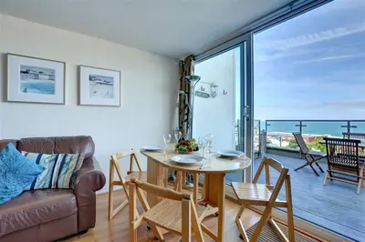 a living room with a table and a couch and a balcony at 2 Bed in Newquay oc-p00214 in Newquay