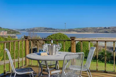a table and chairs on a deck with a view of the ocean at 2 Bed in Padstow oc-p00134 in Padstow