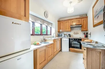 a kitchen with wooden cabinets and a white refrigerator at 2 Bed in Padstow oc-p00249 in Padstow