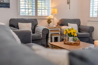 a living room with couches and a table with yellow flowers at 3 Bed in Padstow oc-p00165 in Padstow