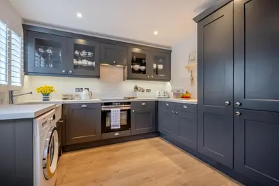 a kitchen with black cabinets and a washer and dryer at 3 Bed in Padstow oc-p00165 in Padstow