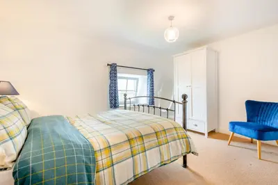 a bedroom with a bed and a blue chair at 3 Bed in Padstow oc-p00294 in Saint Issey