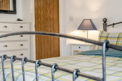 a bedroom with a bed with a lamp and a bedskirtspectspectspectspects at 3 Bed in Padstow oc-p00294 in Saint Issey