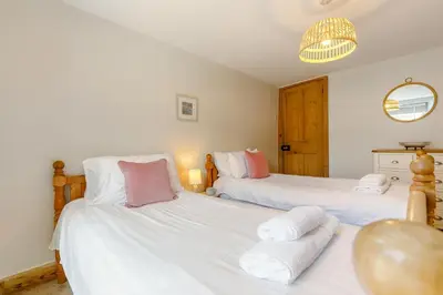 a bedroom with two beds with white sheets and pink pillows at 4 Bed in Padstow oc-p00297 in Padstow